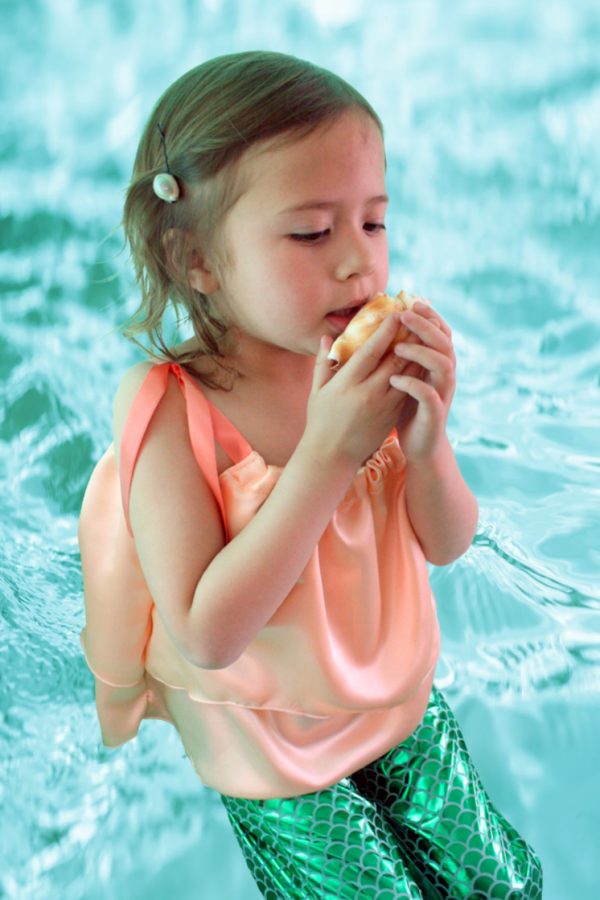 little girl in mermaid costume holding shell